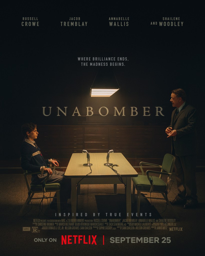 Póster de la serie 'Unabomber', con un joven sentado en una silla frente a una mesa con micrófonos, mientras un hombre mayor de pie lo observa. Ambientación oscura y frases sobre la locura y la brillantez.